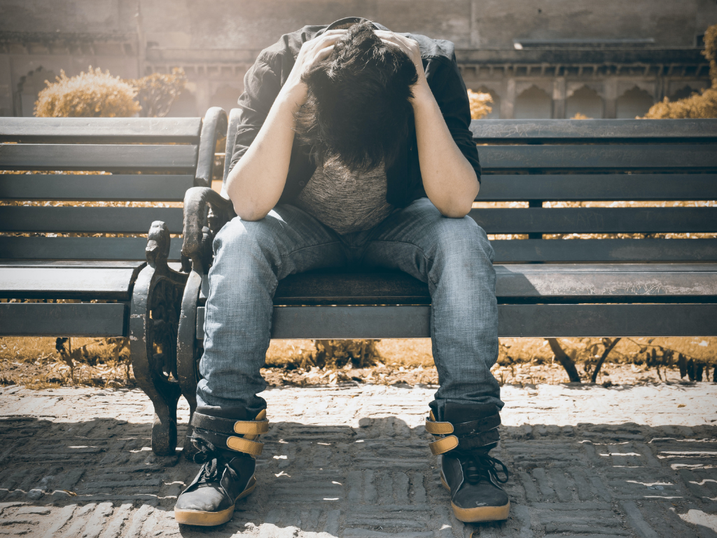 A stressed out man seated in a bench