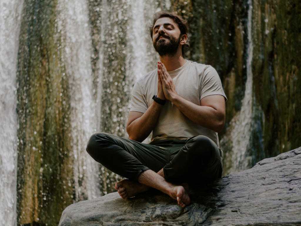 An image of a man near waterfall performing Chakra meditation