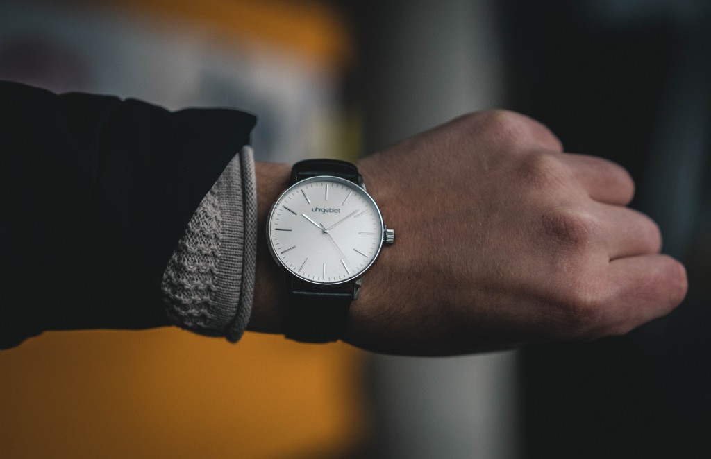 A man showing his watch which indicates 10 minutes past 10