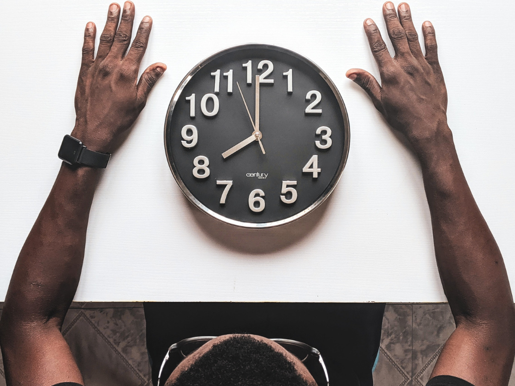 An image of a man watching the clock timer while meditating.