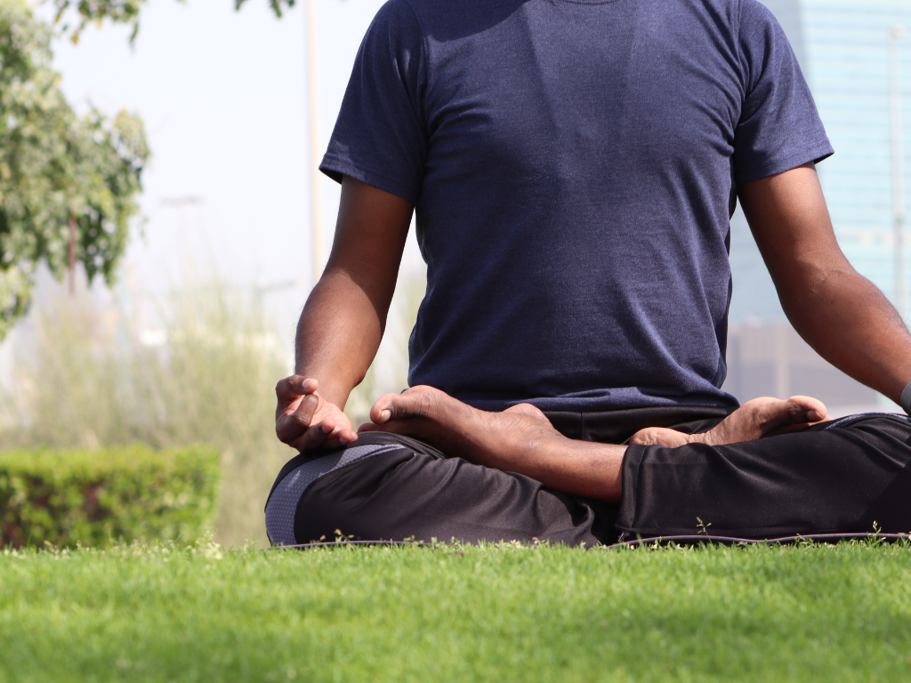 An image e of a man performing meditation in the outdoors