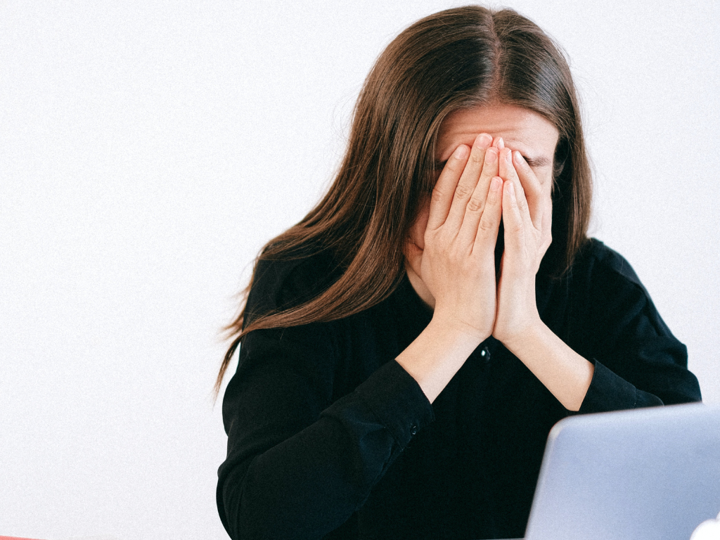 An image of a stressed woman covering her face with her hands.